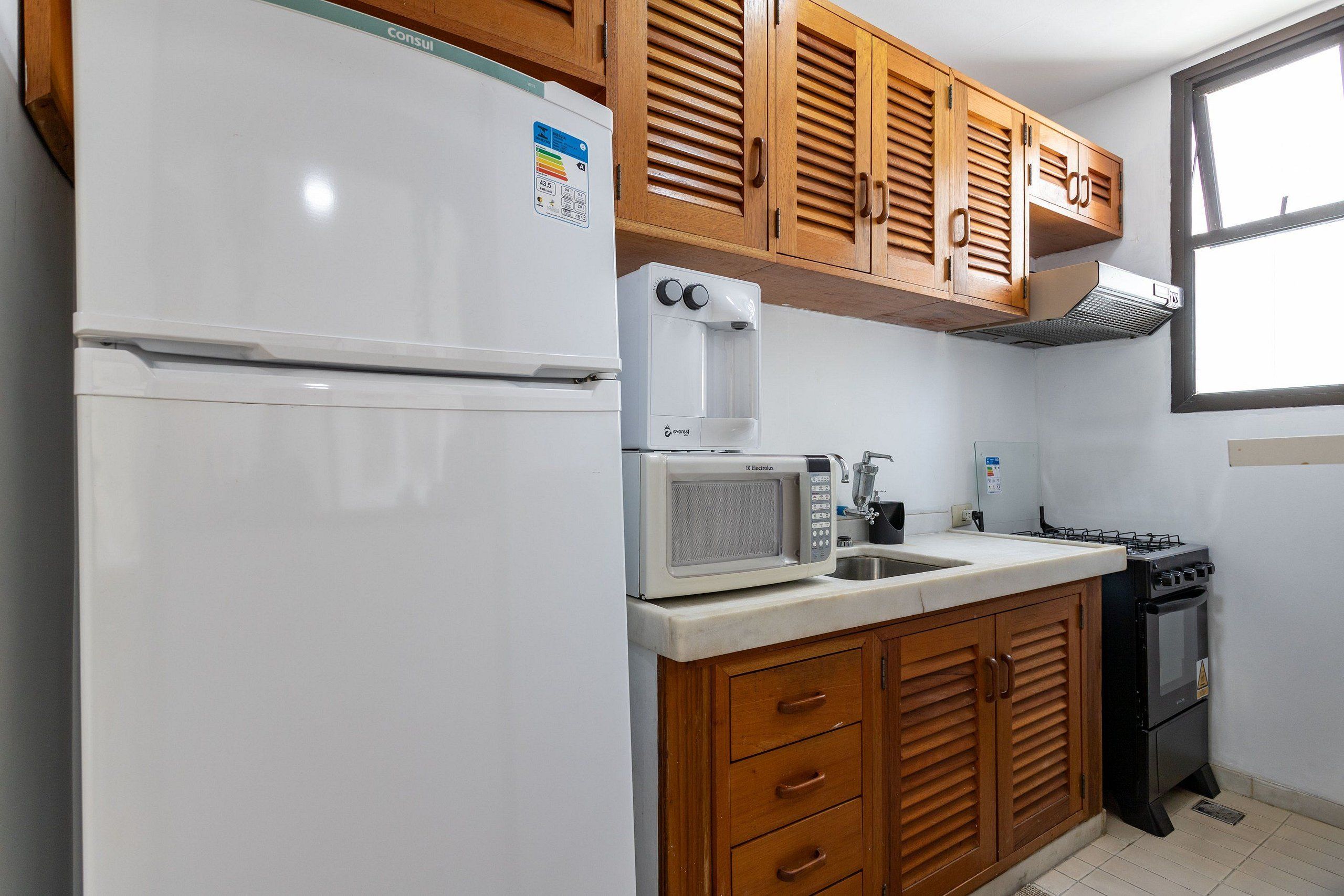 A kitchen with a refrigerator, microwave, stove, and wooden cabinets.