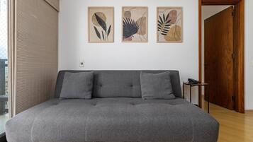 Uma sala de estar moderna com um sofá cinzento, duas almofadas e três impressões botânicas emolduradas na parede.