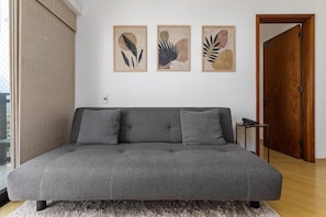 Una sala de estar moderna con un sofá gris, dos cojines y tres láminas botánicas enmarcadas en la pared.