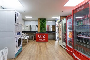 A laundry area with a washing machine, a Kibon branded counter, and a Coca-Cola refrigerator. - (1006) Apartamento com 2 Suítes e Vista para o Cristo (Rio de Janeiro)
