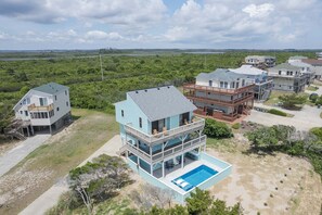 A coastal residential area with multiple houses, including a two-story house with a balcony and a swimming pool.