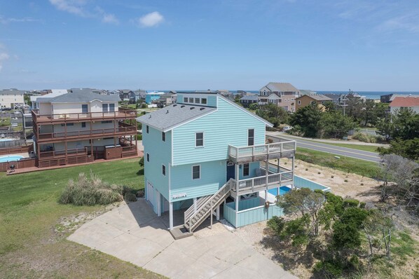 A two-story building with a balcony, a pool, and a clear view of the ocean.