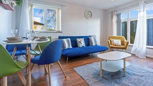 A modern living room with a blue sofa, green and blue chairs, a white table, and a chandelier. - 1bed-sleeps3 Parking-nearcitycentre-jlr-nec (Birmingham)