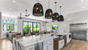 A modern kitchen with a large island, stainless steel appliances, and black pendant lights. - 🩵🌴 Peaceful Palms | New Build | Heated* Pool & Golf Cart | Free Dolphin Cruise 🐬 (Miramar Beach)