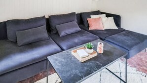 A modern living room with a dark grey sectional sofa, a small coffee table with a plant and a book, and a white radiator above the sofa. - 2 bedroom amazing home in Kolind (Kolind)
