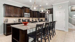 A modern kitchen with dark wood cabinets, stainless steel appliances, and a granite countertop. - Spacious Resort Home for Large Groups near Disney (Kissimmee)