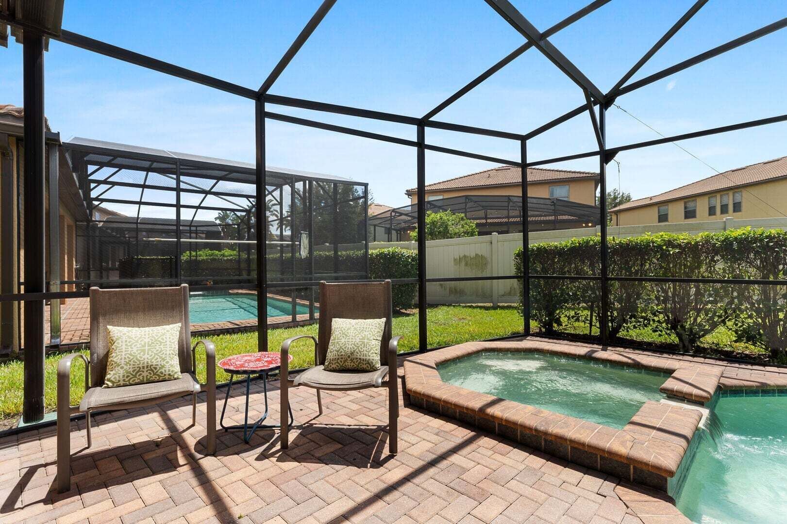 A covered outdoor area with a pool, two chairs, and a hot tub.