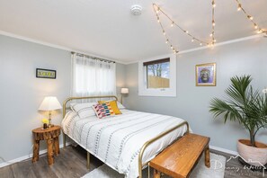 Cozy retreat with a neatly made bed, wooden bench, and a potted plant.