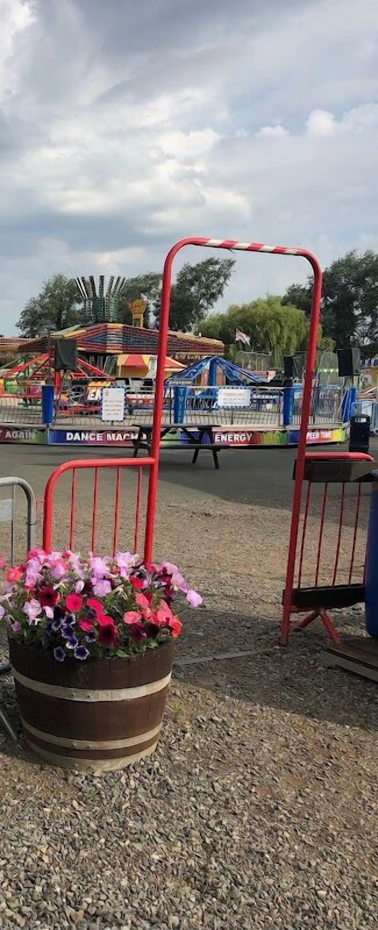 A playground with a red and white striped barrier, a flower pot with pink and purple flowers, and a sign that reads "DANCE MACHINERY".