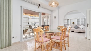 A dining area with a glass table surrounded by wooden chairs with cushioned seats, a hanging light fixture, and a view through a glass door to an outdoor balcony. - Apartment 'Laolita' with Sea View, Wi-Fi and Air Conditioning (Torrox)