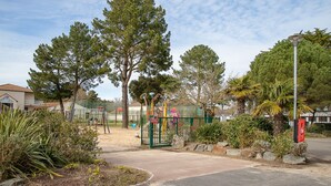A playground with climbing structures, a fenced area, and a street lamp.