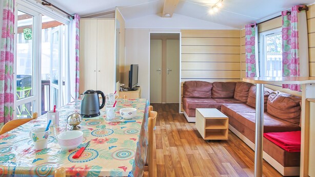A compact living space with a dining table, a sofa, a television, and a small table.