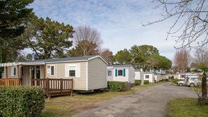 A row of mobile homes with a gravel driveway, wooden fences, and a car parked nearby.