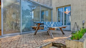 Eine Terrasse mit Tisch und Stühlen, eine Betonmauer und eine große Glastür.
