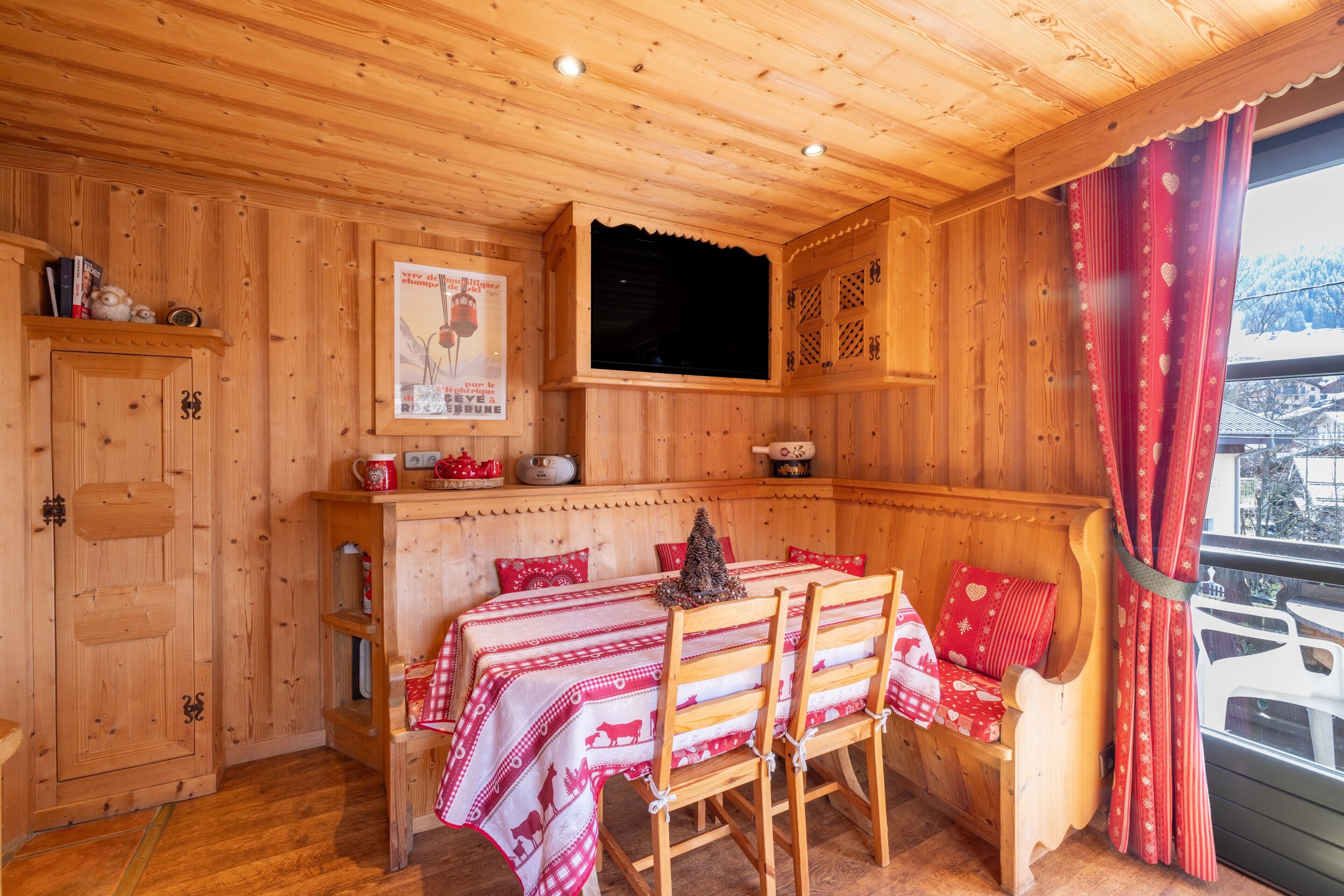 Un intérieur en bois comprenant une table, des chaises, un banc et une fenêtre avec des rideaux.