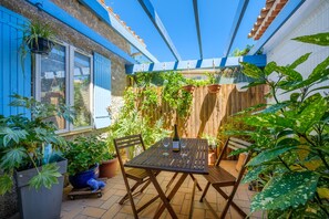 Eine Terrasse mit Tisch und Stühlen, umgeben von Kübelpflanzen und einem Holzzaun.