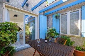 Eine Terrasse mit Tisch, zwei Weingläsern und einer Weinflasche.