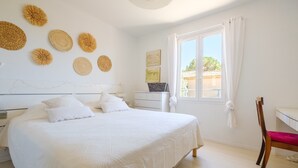 Ein Schlafzimmer mit Bett, Schreibtisch, Stuhl, einem Fenster mit Vorhängen und Wanddekorationen.