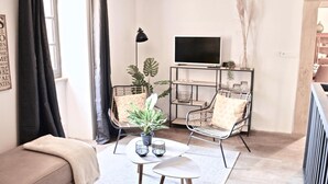 A modern living room with a sofa, two chairs, a coffee table, a TV, and a plant.