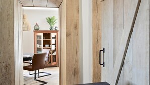 A wooden door with a black handle, a dining area with a table and chairs, and a cabinet with glass doors in the background.