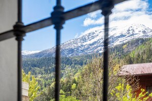 Eine Berglandschaft mit einer Holzhütte und einem schneebedeckten Gipfel im Hintergrund.