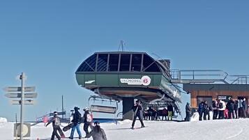 Eine Seilbahn mit wartenden Personen, ein Holzboden und ein Schild für Valmorel.