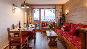 Ein gemütliches Zimmer mit einem Holzesstisch, Stühlen, einer Couch und einer Bank.