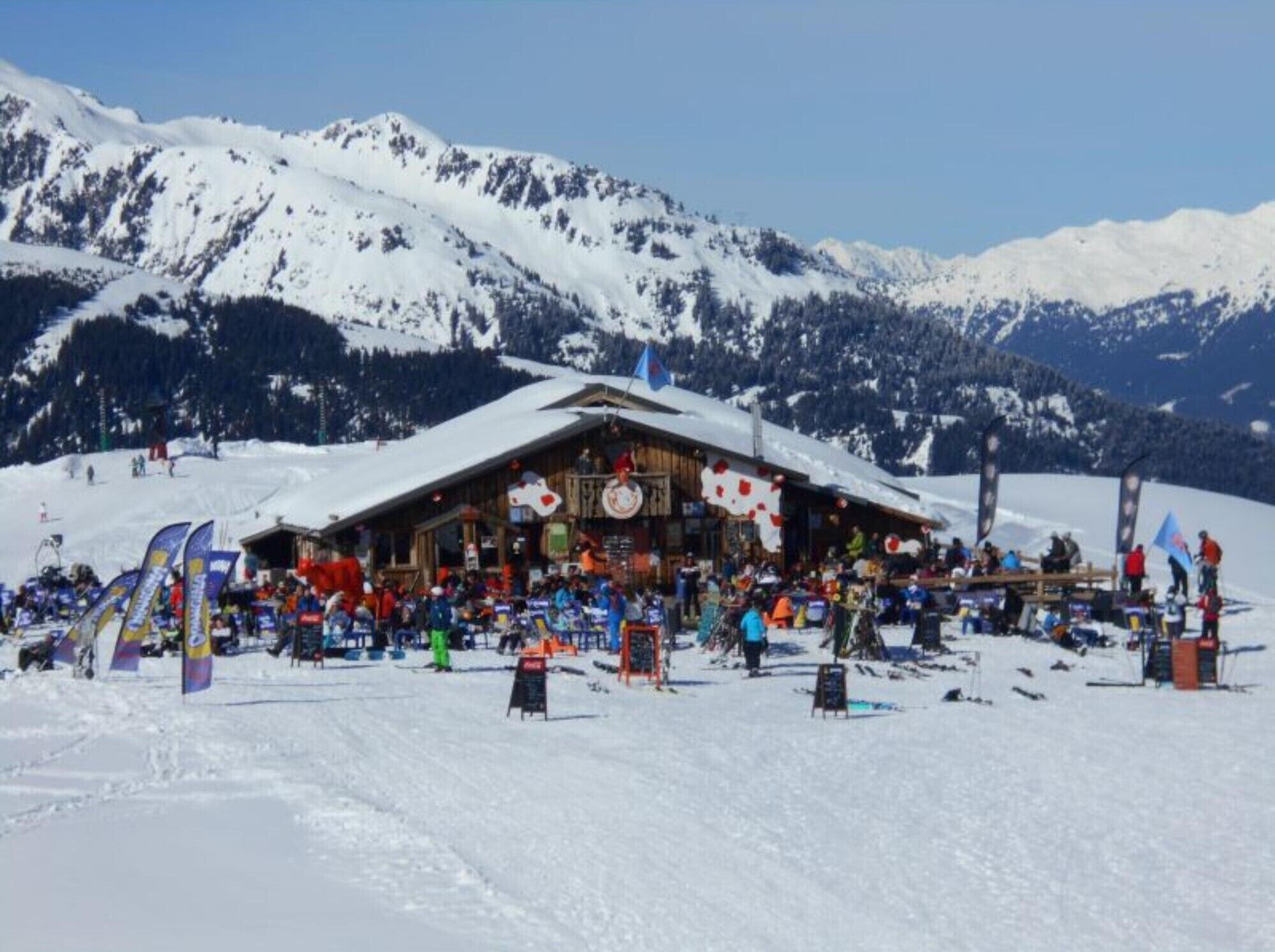 Une montagne enneigée, avec un bâtiment en bois au premier plan.