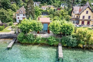 Una propiedad junto al lago con un muelle, un edificio central con puerta roja y casas circundantes.