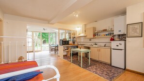 Une cuisine moderne avec des meubles en bois, un réfrigérateur et un coin repas comprenant une table et des chaises.