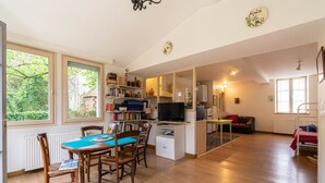 Une pièce spacieuse comprenant une table à manger, des chaises, un téléviseur et un coin salon confortable.