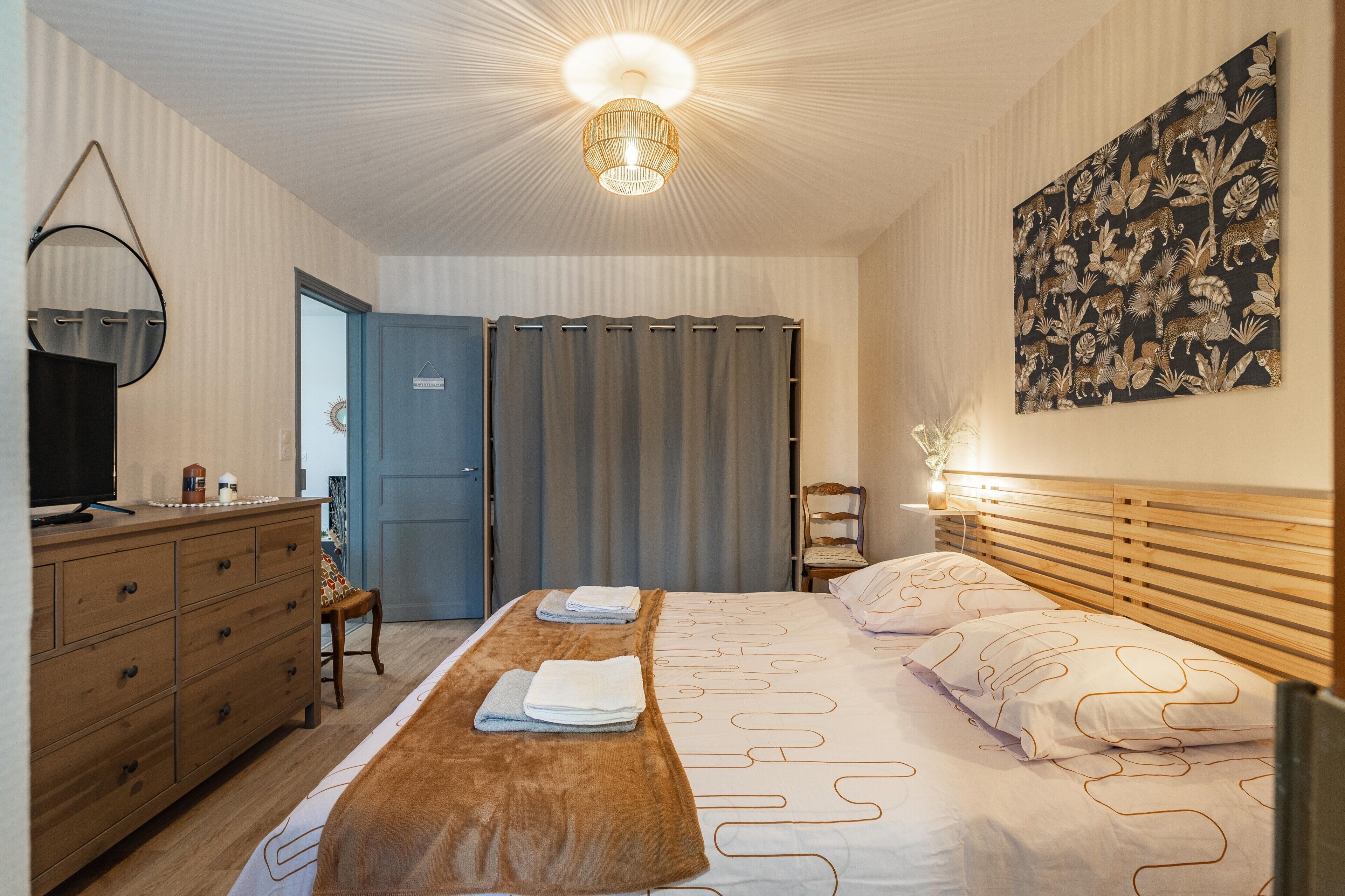 Een hotelkamer met een bed, een houten dressoir, een televisie en een kunstwerk aan de muur.