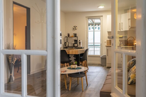 A modern kitchen with a dining area, a coffee machine, and a clock on the wall.