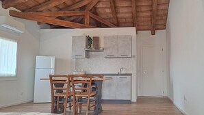 Una cocina con sillas de madera, un refrigerador blanco y una encimera gris.