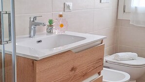 Un baño moderno con tocador de madera, cabina de ducha de vidrio y un inodoro blanco.