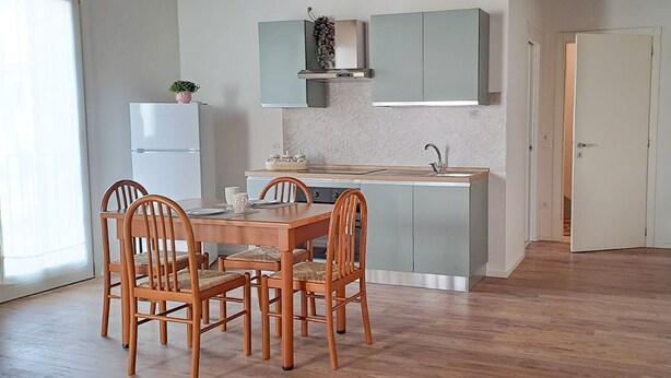 Una cocina compacta con una mesa y sillas, un refrigerador y un lavamanos.