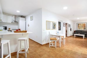 A modern kitchen with white cabinets, a stainless steel range hood, and a breakfast bar with stools.