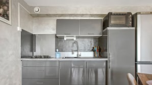 Een moderne keuken met grijze kastjes, een roestvrijstalen koelkast, een inbouwoven en een spoelbak met een kraan.