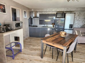 A modern kitchen with a wooden dining table, grey cabinets, and a microwave.