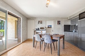 A modern kitchen with a dining area, large windows, and a view of the outdoors.