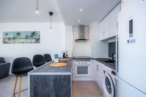 A modern kitchen with a central island, built-in oven, and washing machine.