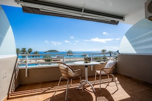 A balcony with a view of the sea, two wicker chairs, a small table, and a white ceiling fan. - First Line Cosy Apartment with Sea Views, Wi-Fi and Air Conditioning (Calvià)