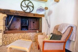 Interior rústico com parede de pedra, mobiliário de madeira e lareira.