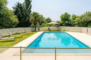 A rectangular swimming pool with a tiled edge, surrounded by a fence, and shaded by a single umbrella. - Cottage 'Lou Tapata' with Shared Pool, Private Terrace and Wi-Fi (Panjas)