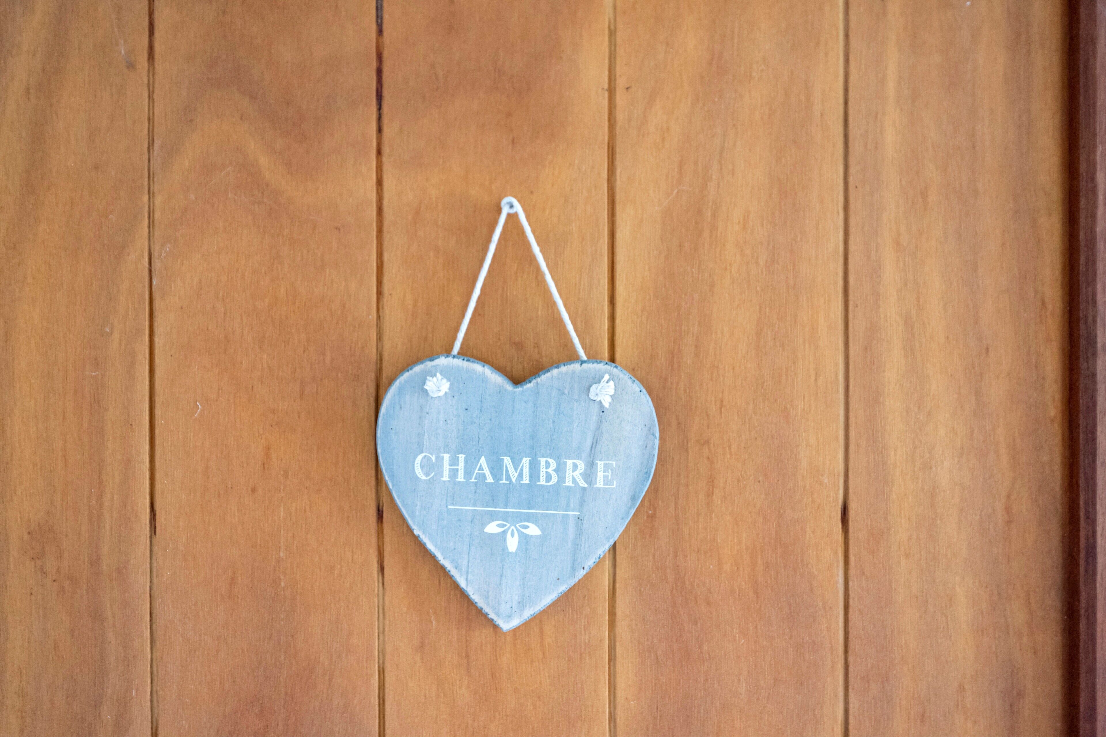A heart-shaped sign with the word 'CHAMBRE' hanging on a wooden wall.