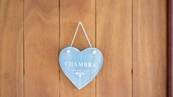 Una señal con forma de corazón que dice 'CHAMBRE' colgada en una pared de madera.