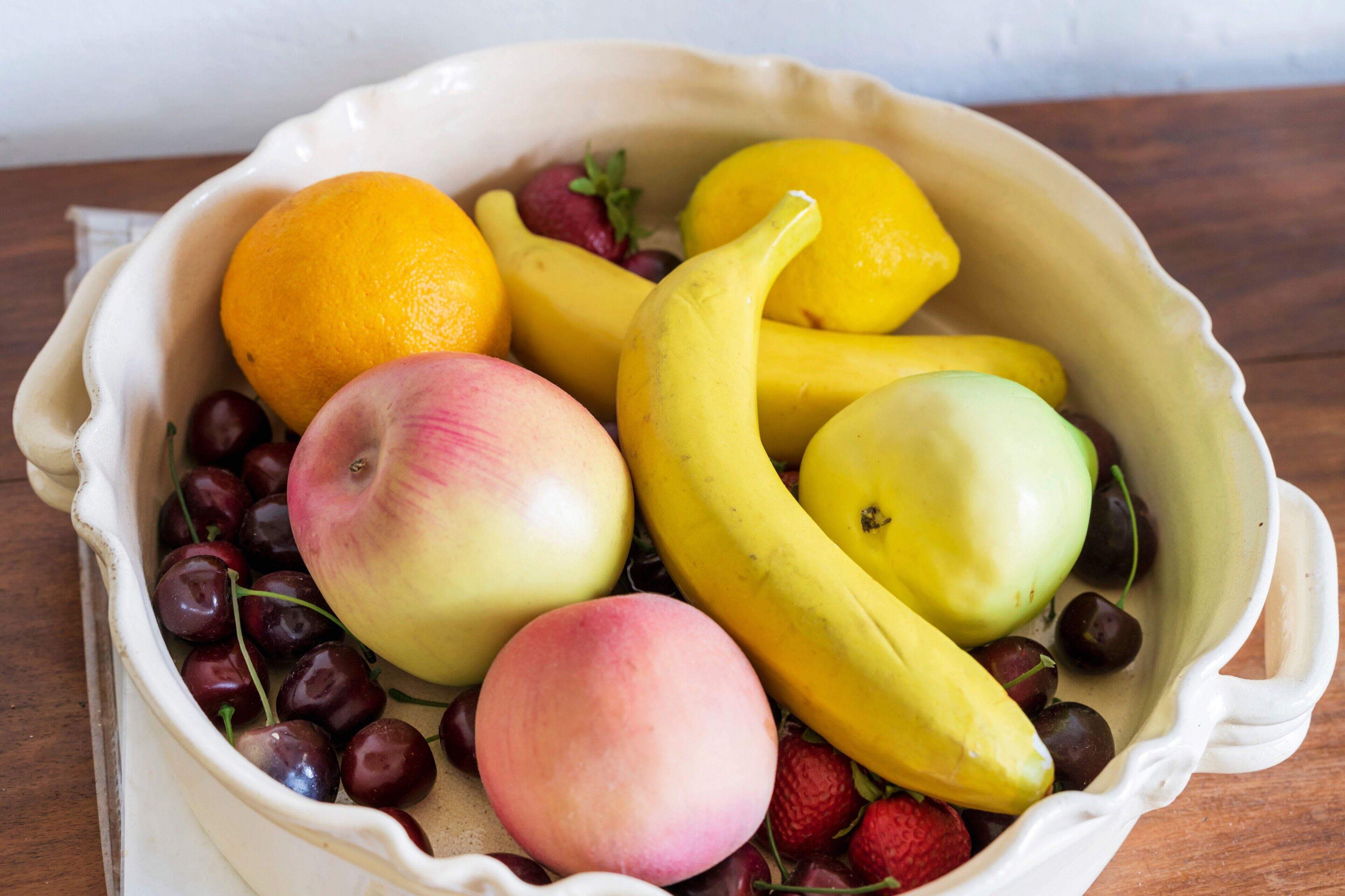 A bowl of assorted fruits including apples, bananas, cherries, and grapes.