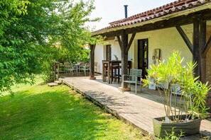 Um alpendre coberto com área de estar externa, um deck de madeira e um vaso com planta.