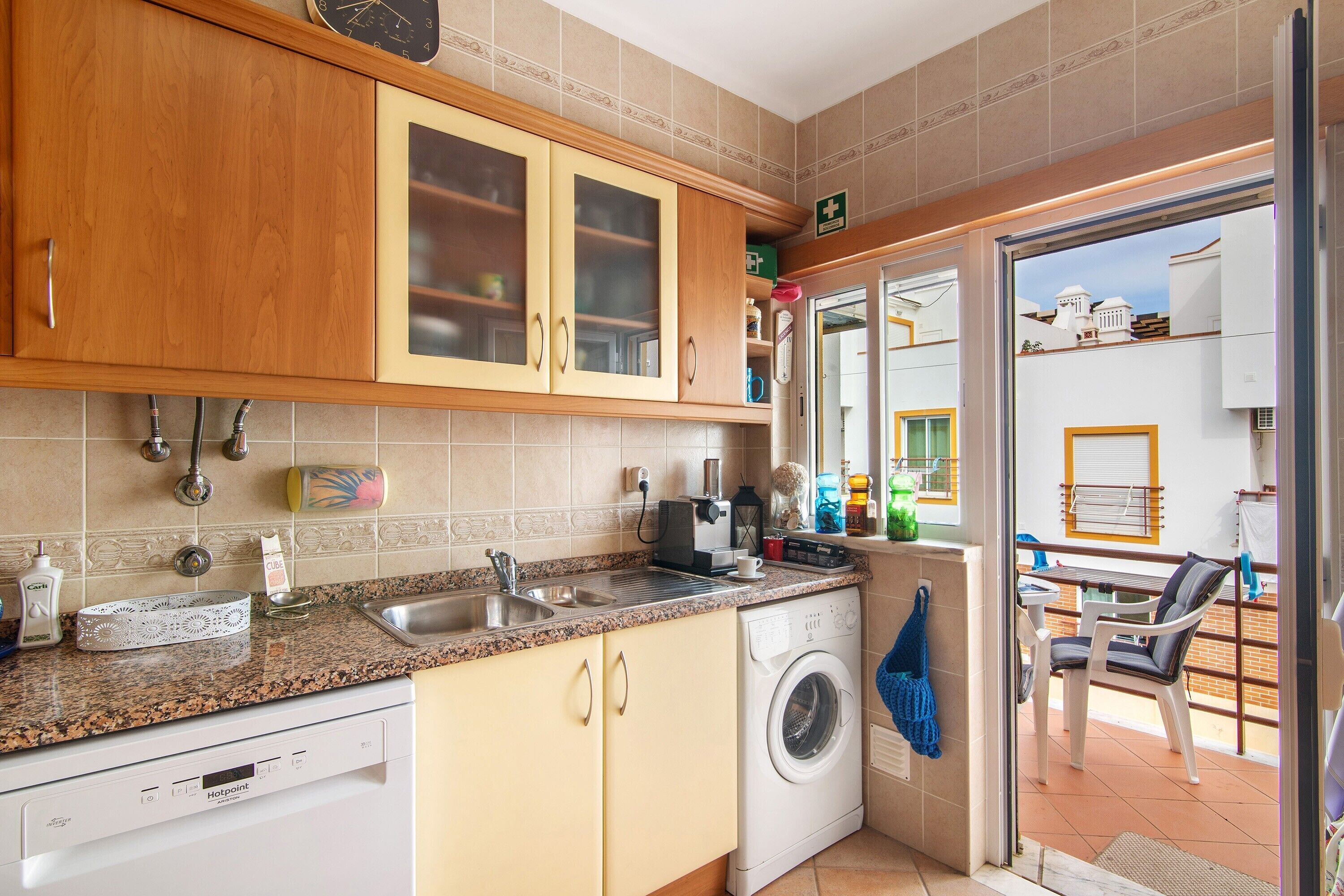 A compact kitchen with a dishwasher, washing machine, and a coffee maker.