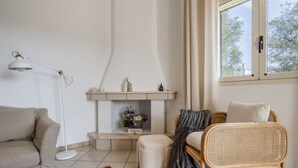 A living room with a sofa, a chair, a floor lamp, a fireplace, and a window with curtains.